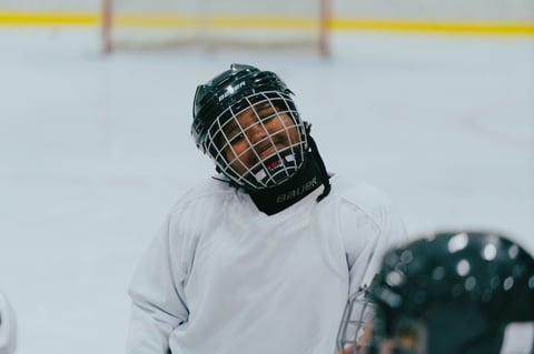 Young hockey player wearing black helmet and white jersey on ice rink