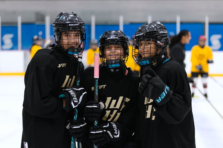 Three youth hockey players in black jerseys with gold stripes standing together on ice during a game