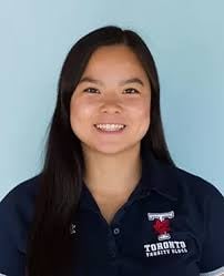 Woman with long dark hair smiling at camera wearing dark blue polo shirt with emblem against light blue background