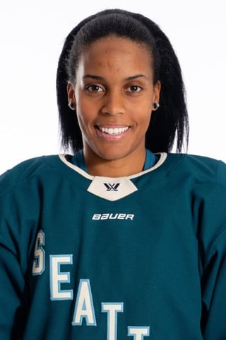 Portrait of a smiling female hockey player wearing a teal Bauer team jersey with white trim