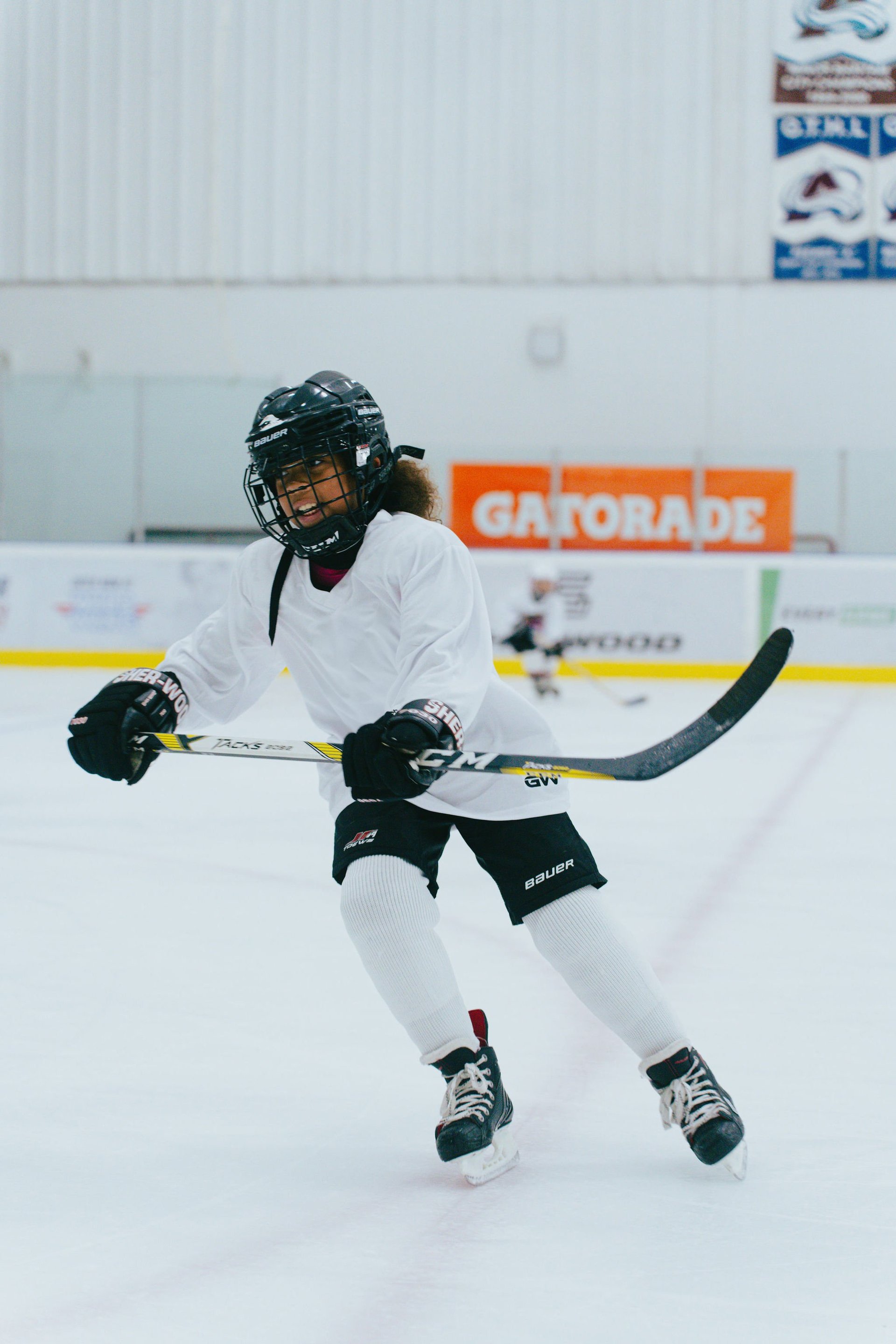 Young hockey player in white jersey and black helmet skating on the ice